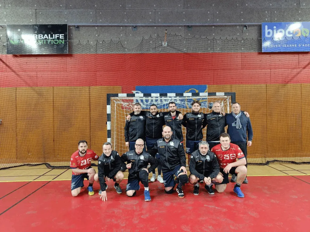 Photo de l'équipe de Rouen Handball devant les buts, équipée grâce au don de BearStudio, avec Quentin parmi les joueurs