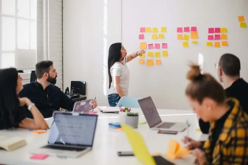 Échange d'idée en réunion autour de post-it collés sur un tableau